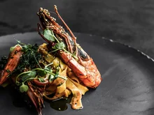 Der Salnerhof – das Hotel in Ischgl Garnelen auf Pasta mit grünen Kräutern auf schwarzem Teller
