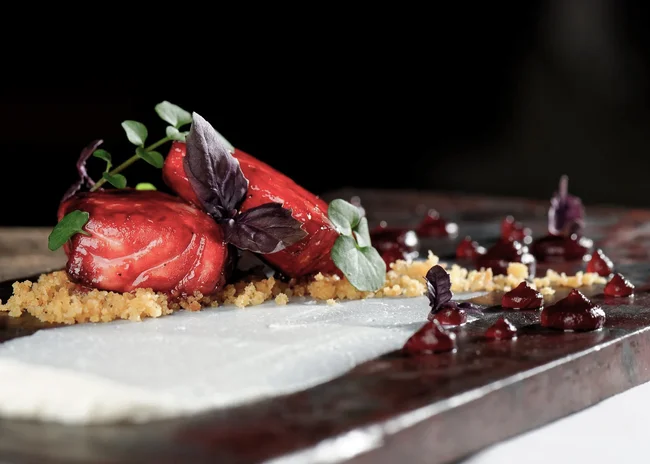 Der Salnerhof – das Hotel in Ischgl Fein angerichtete Gourmet-Vorspeise mit roten Beeren und Kräutern auf schwarzem Teller