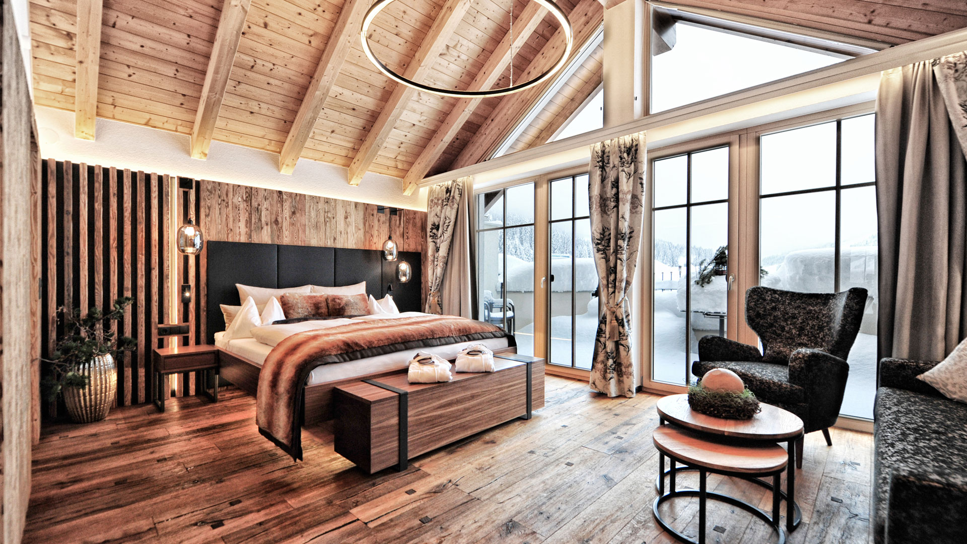 Großzügiges, helles Superior-Doppelzimmer mit Panoramafenstern, Holzdecke, elegantem Bett und gemütlichem Sessel
